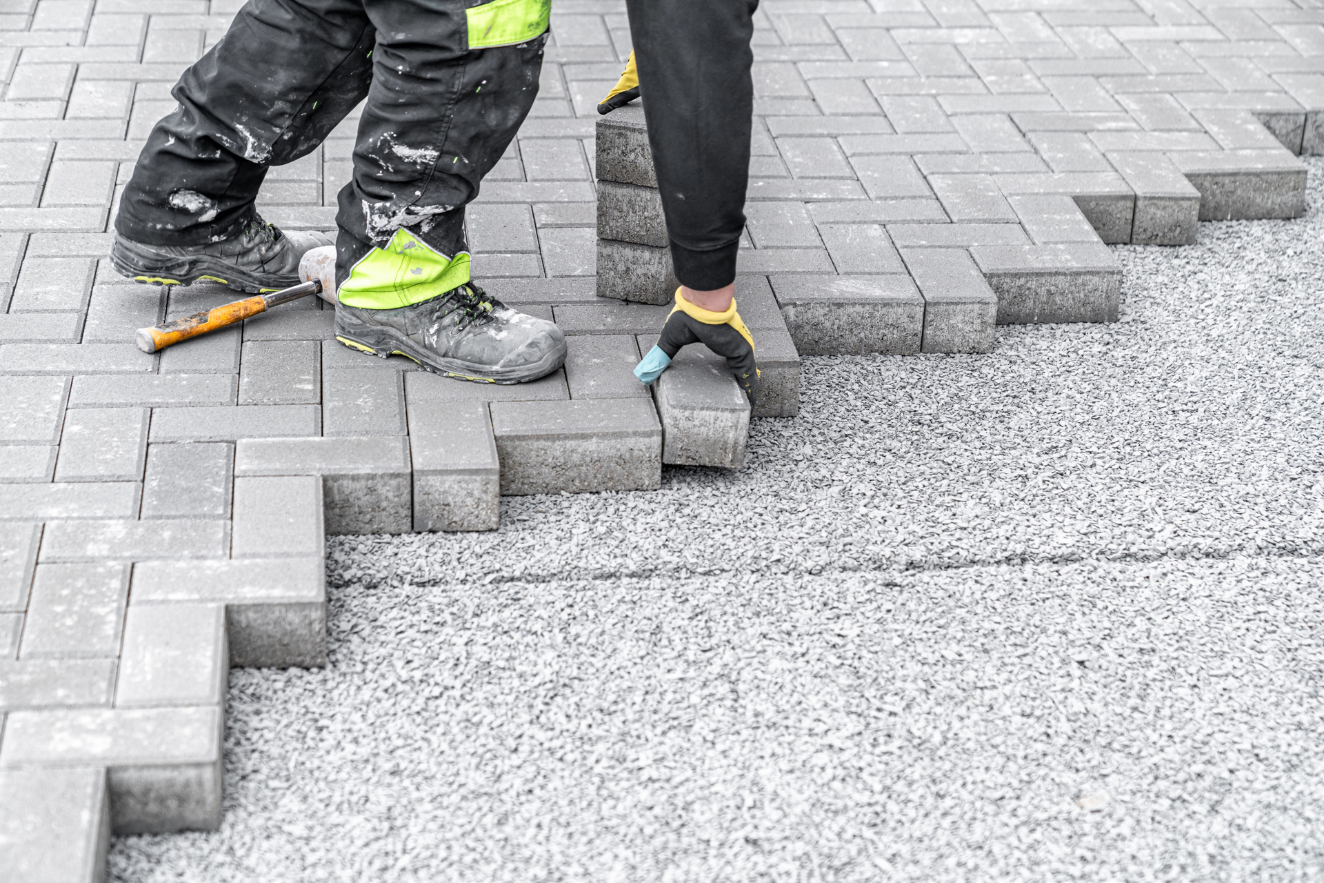 A man is laying bricks on a sidewalk.