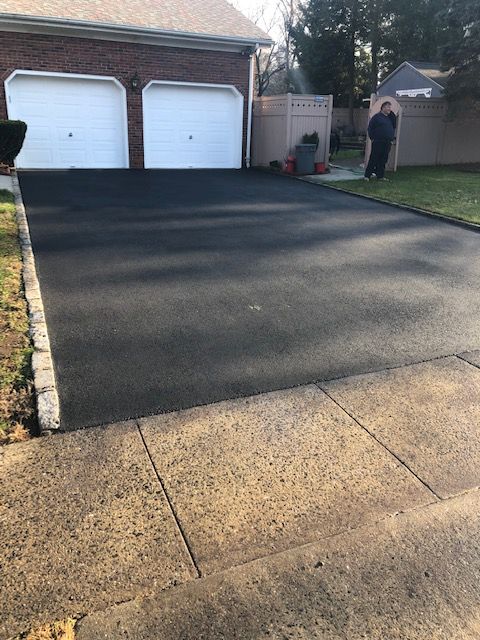 A man is standing in the driveway of a house.