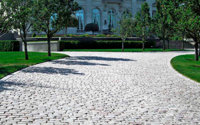 A cobblestone driveway leading to a large white house