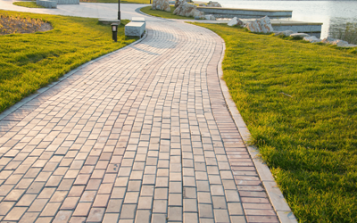 A brick walkway leading to a lake in a park