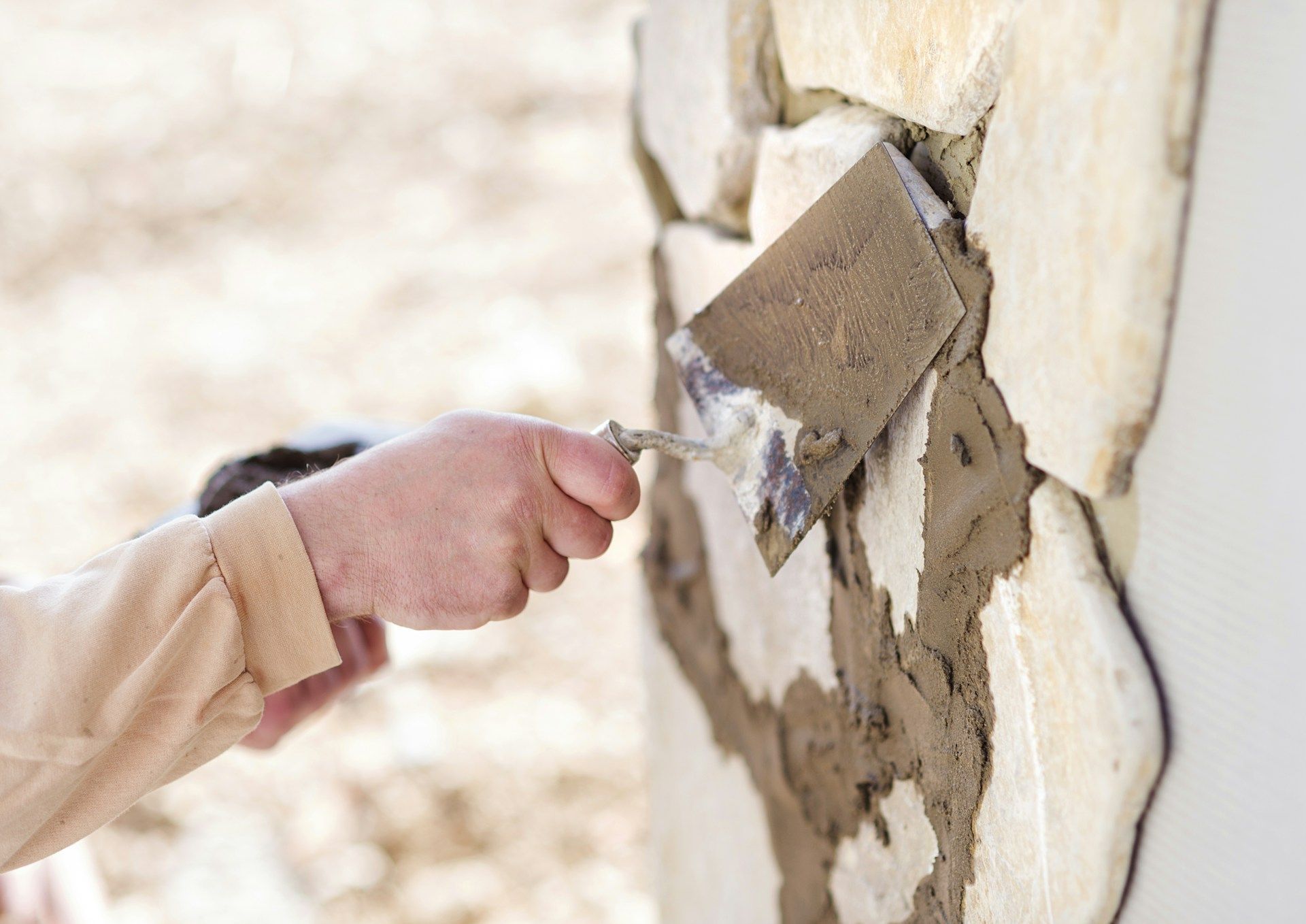 A person is plastering a wall with a trowel.