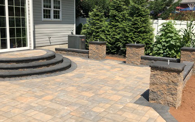 A patio with steps and pillars in front of a house.
