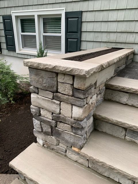 A stone wall with stairs and a window in the background.