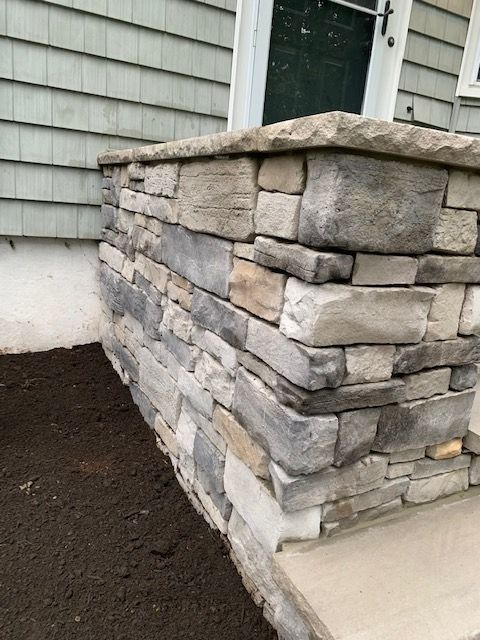 A stone wall next to a house with steps leading up to it.