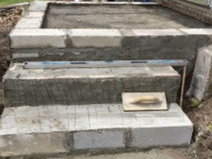 A concrete staircase is being built with bricks and a level.