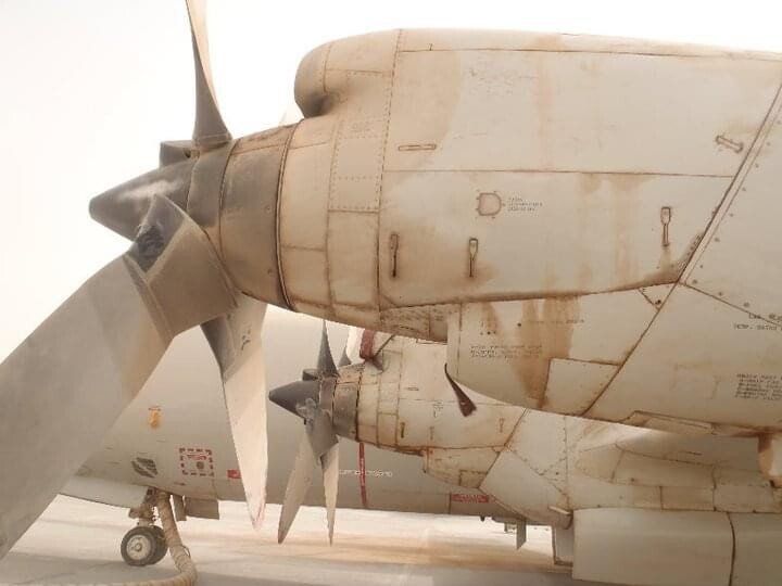 A model airplane is parked on a runway with its propeller missing.