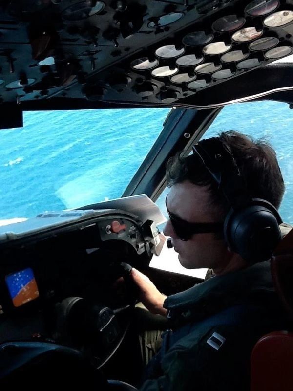 A man wearing headphones is sitting in the cockpit of an airplane