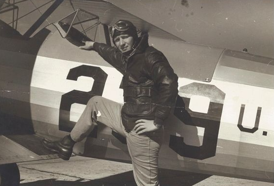 A black and white photo of a man standing next to a plane with the number 29 painted on it