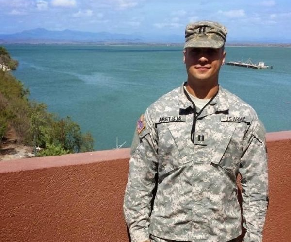 A man in a us army uniform stands in front of a body of water