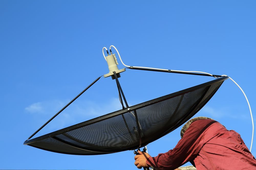 A Man Installing a Satellite Dish — Coffs Coast Antenna Services in Macksville, NSW