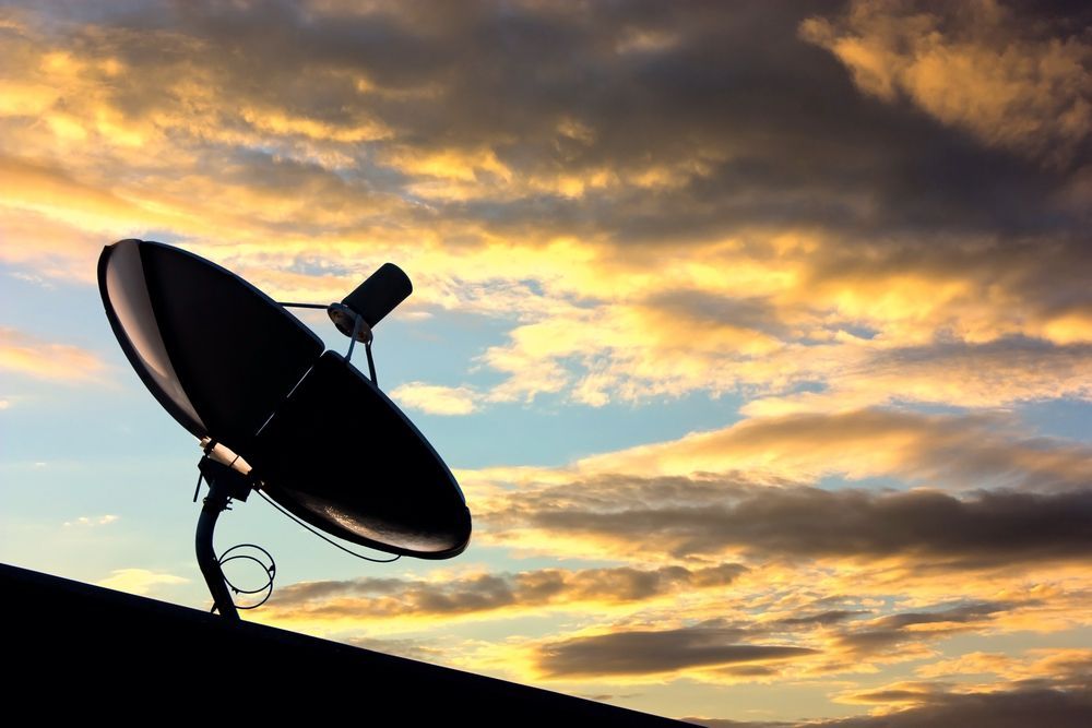 A Satellite Dish is Sitting on Top of a Roof at Sunset — Coffs Coast Antenna Services in Coffs Harbour, NSW