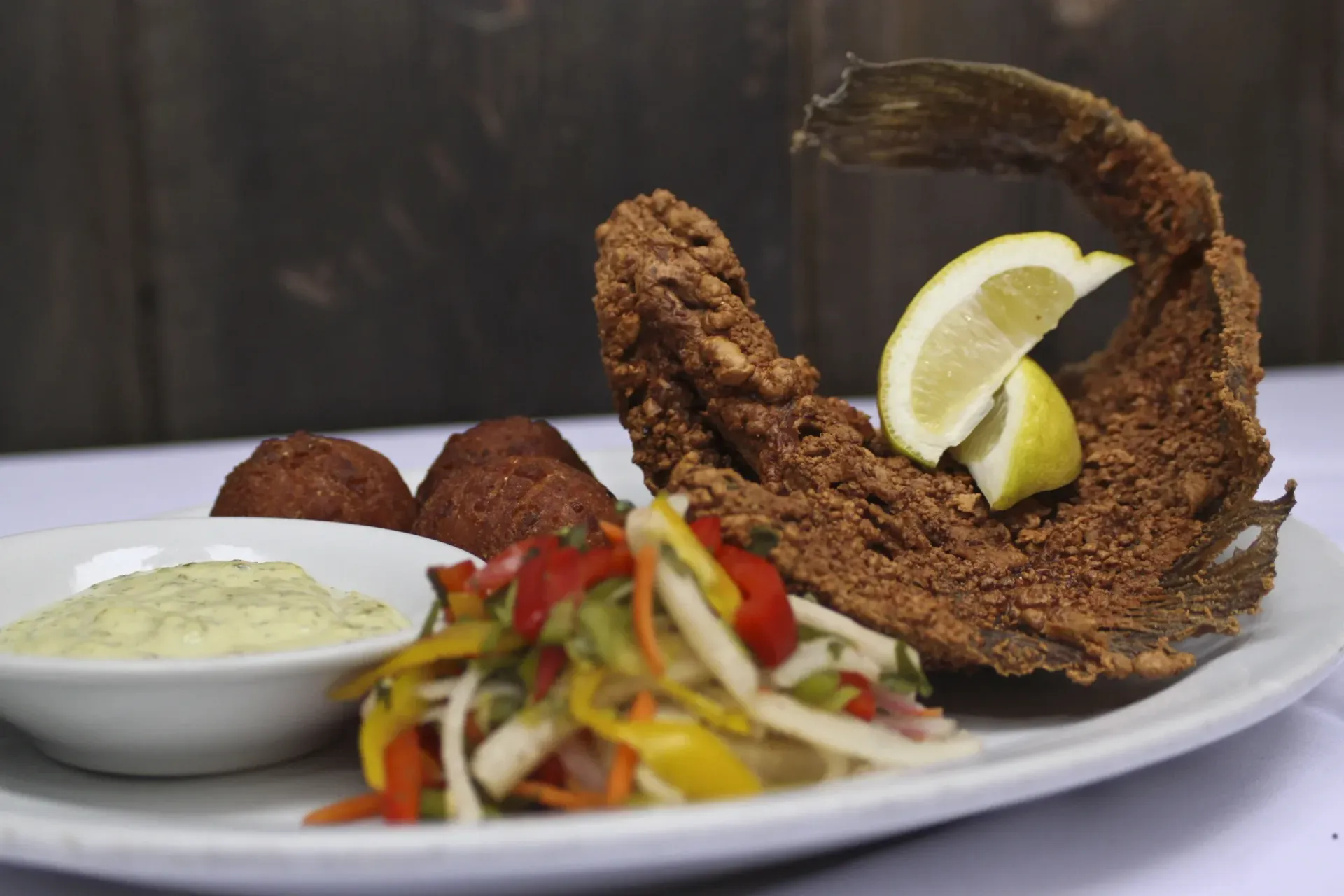 A white plate topped with fried fish and vegetables