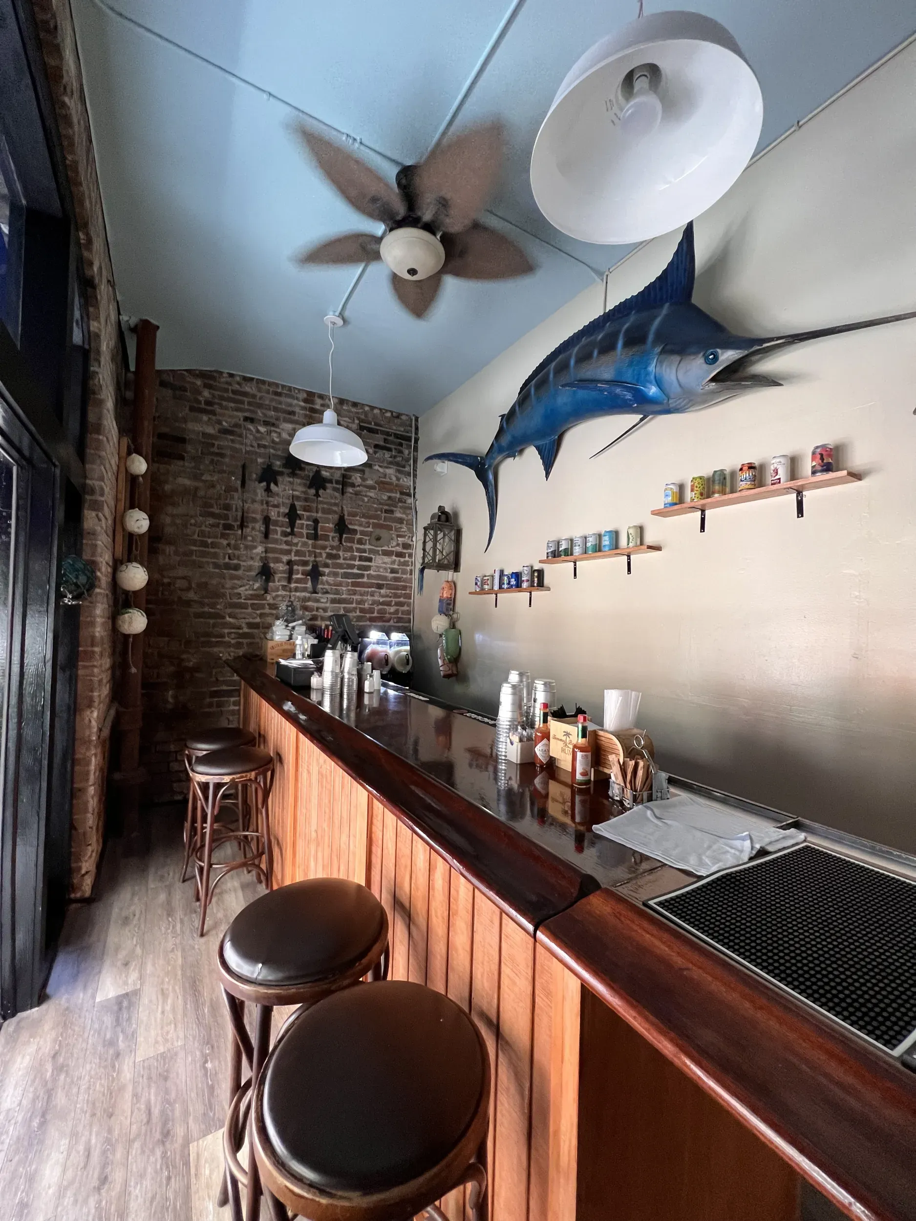 A bar with stools and a large fish on the wall.