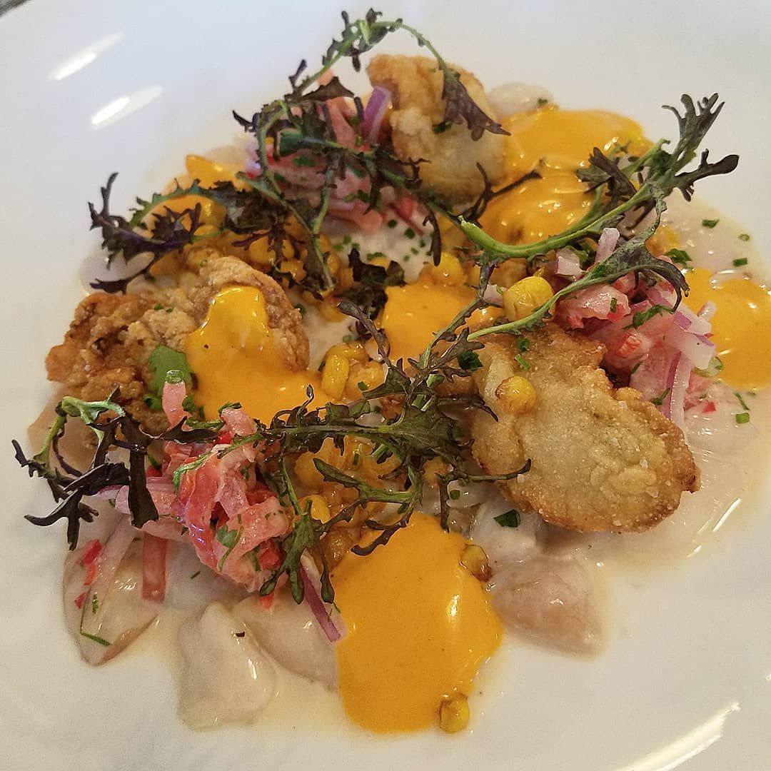 A white plate topped with oysters , lemon slices and sauce.