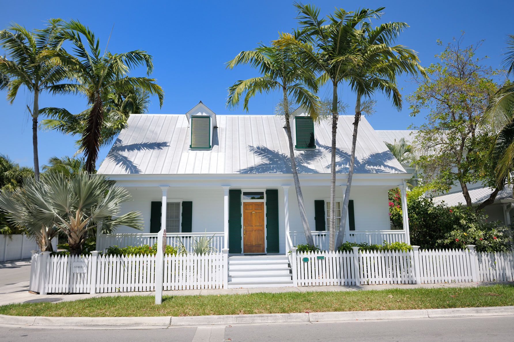 A white house with green shutters and a white picket fence
