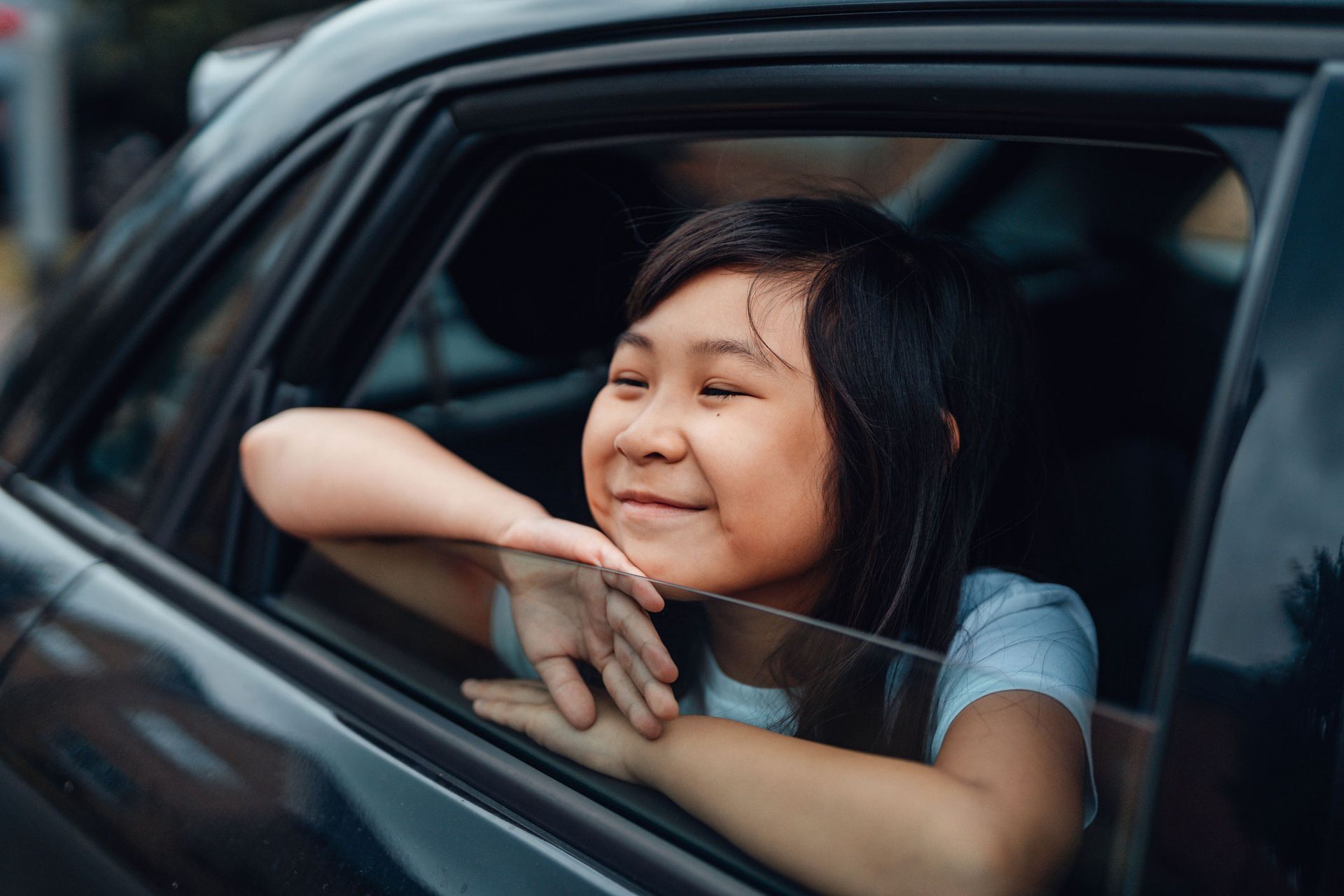 A little girl is looking out of the window of a car.