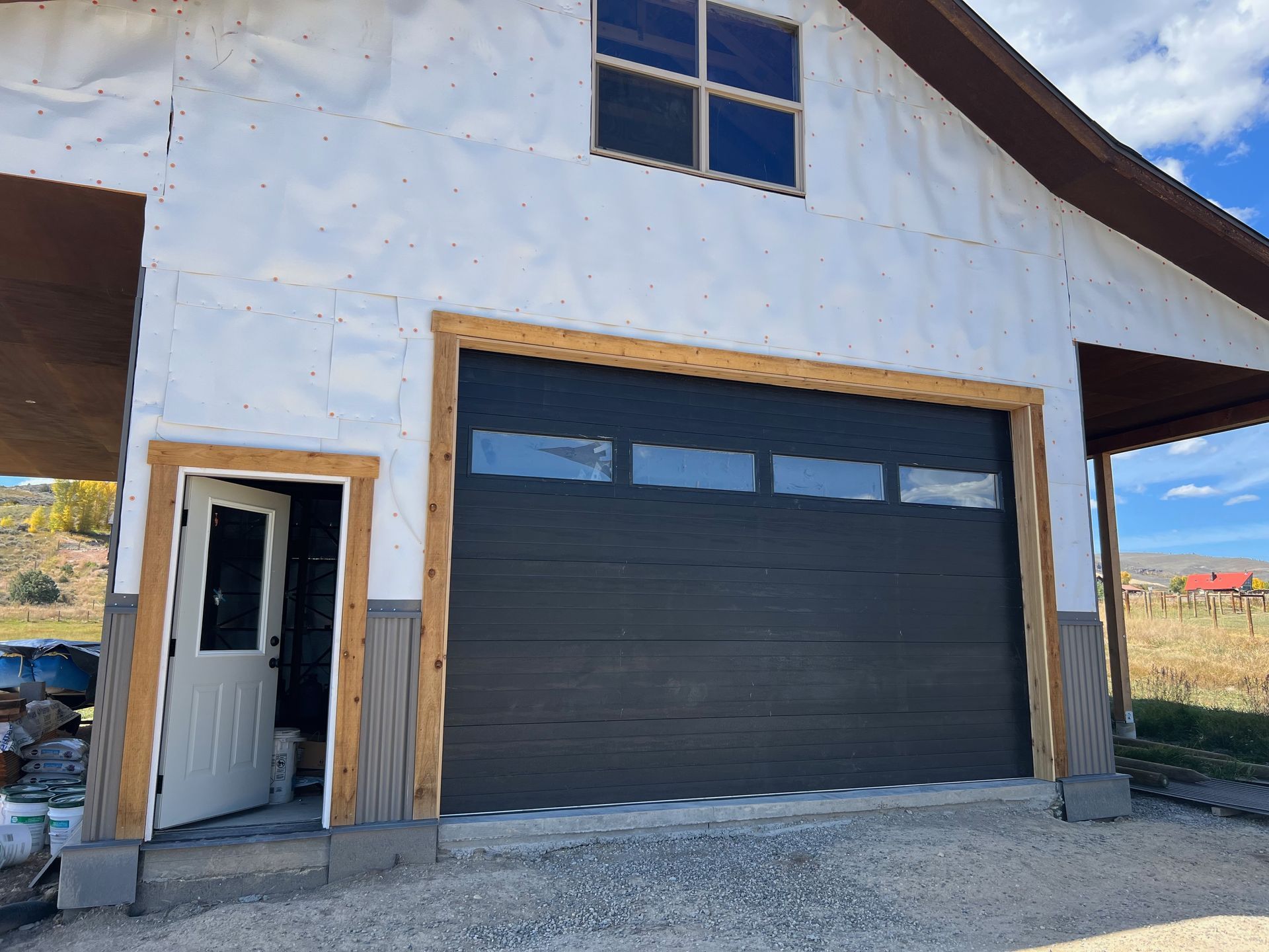 A wooden garage door is sitting in front of a black building.