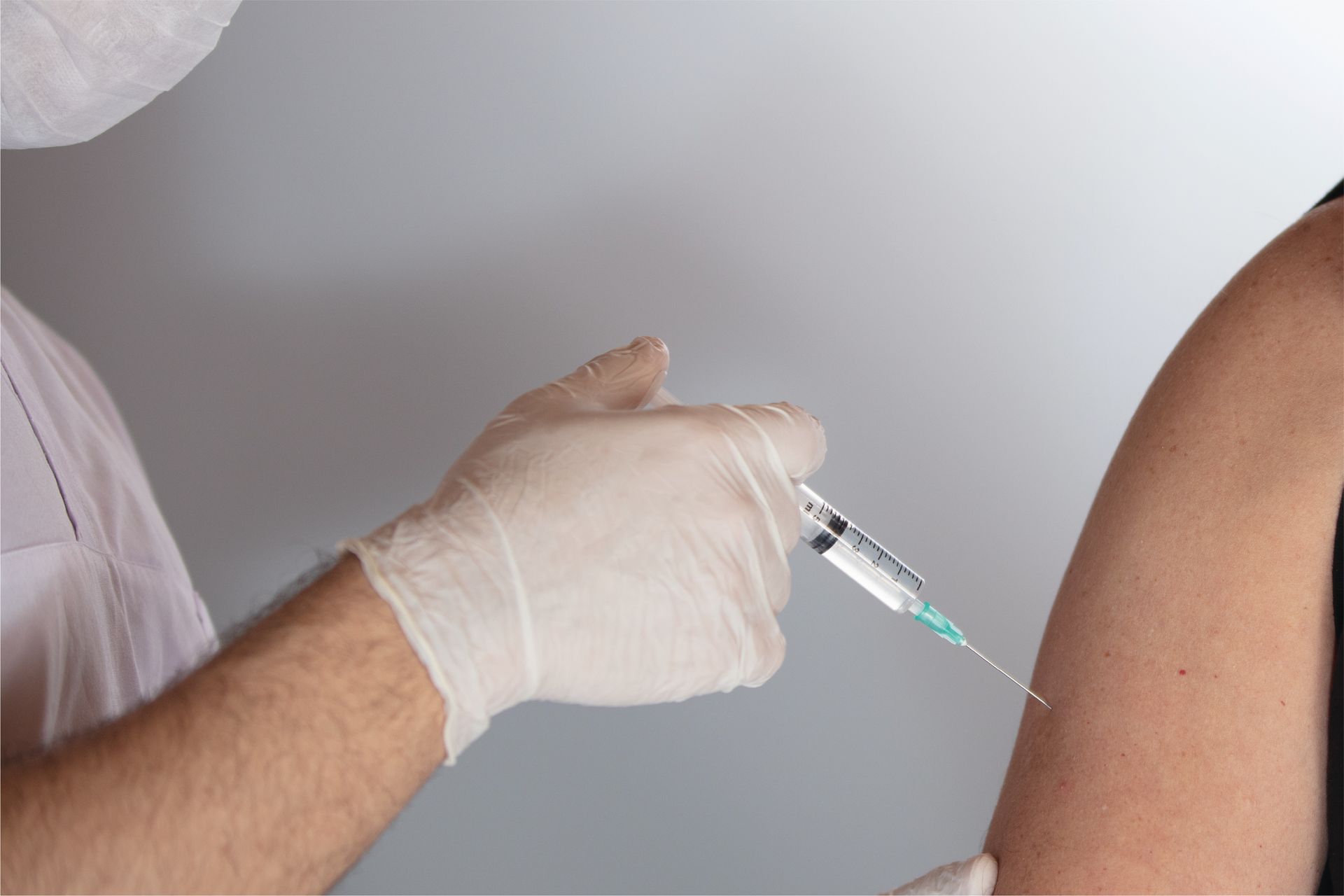Gloved healthcare worker giving an injection in an upper arm