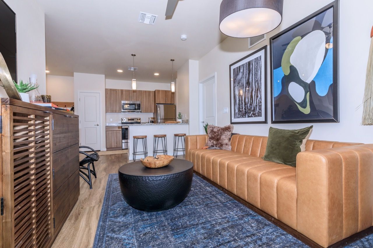 Open-concept living room with tan leather sofa, abstract art, and a kitchen island.