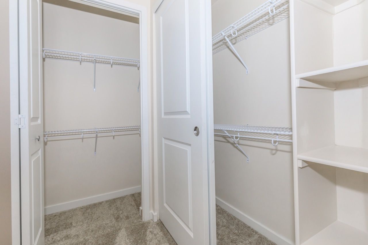 Two open closets with white wire shelves and a built-in shelving unit on the side.