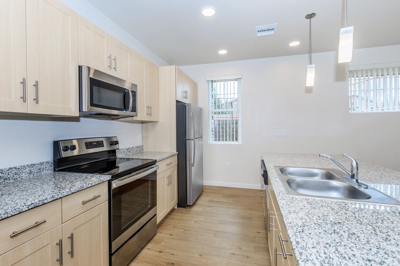 Modern kitchen with granite counters, stainless steel appliances, and an island sink.