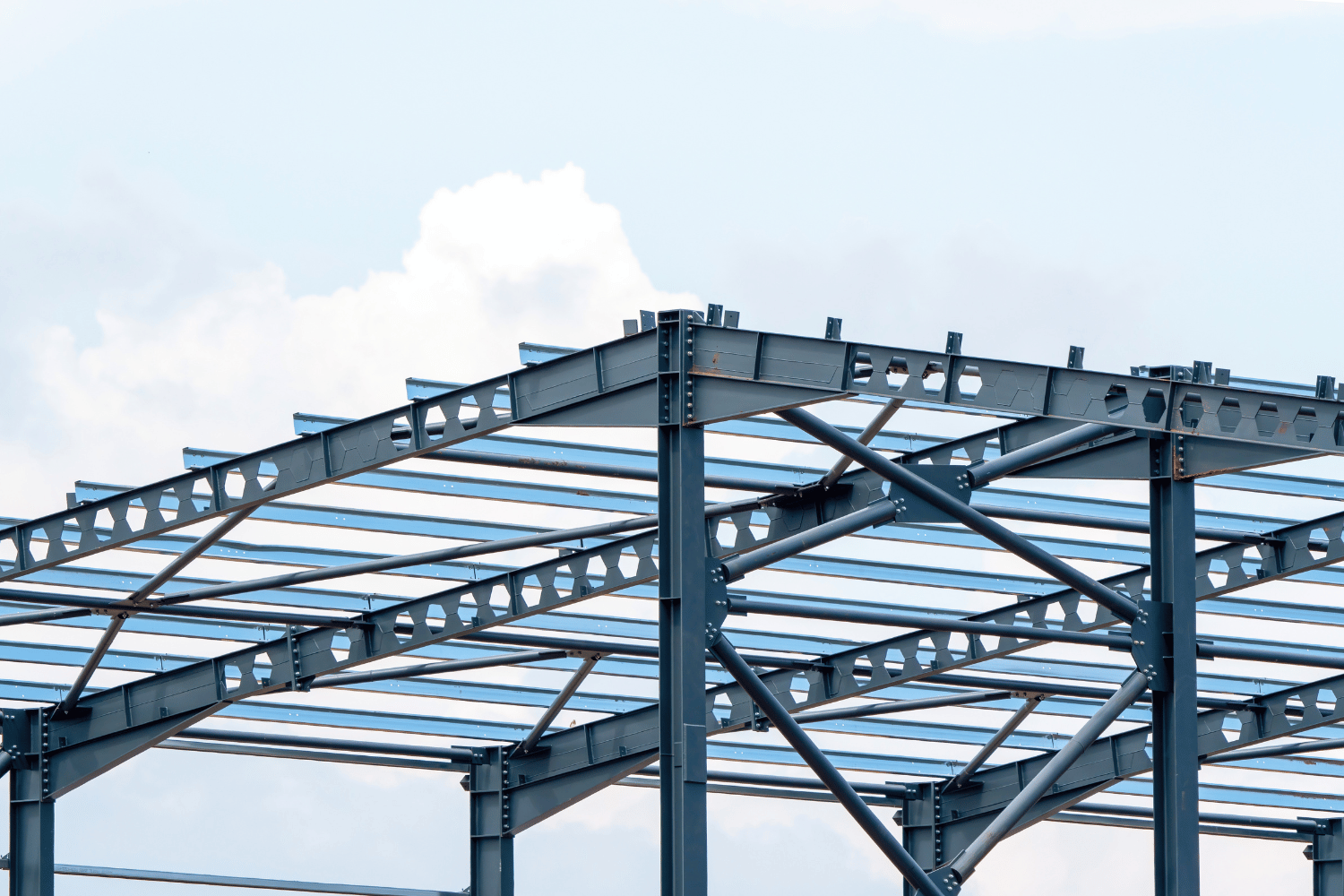 Steel building framework against a cloudy blue sky