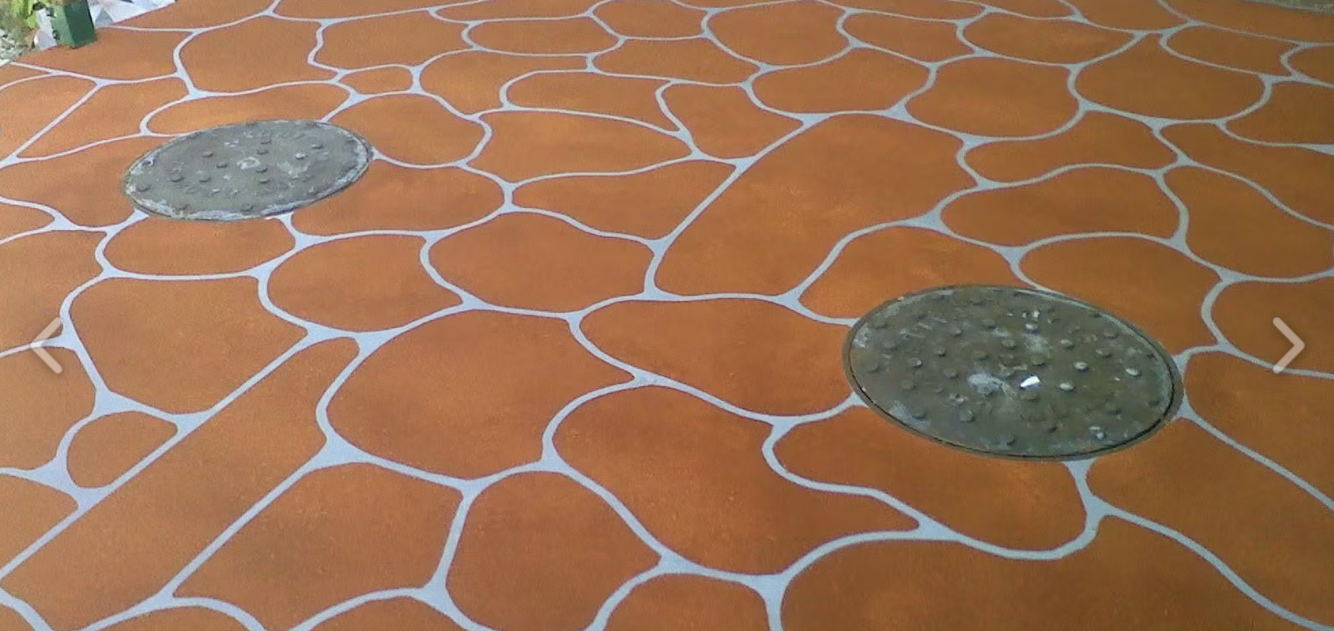 Orange floor with white vein-like lines and two round metal drain covers