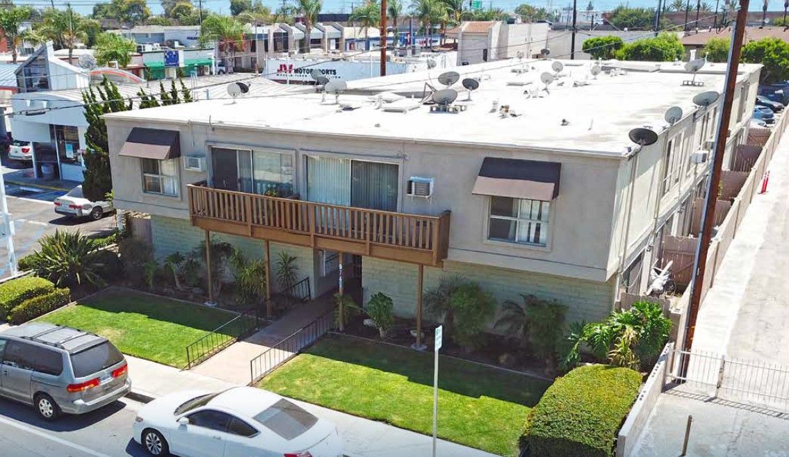 An aerial view of a large apartment building with cars parked in front of it.