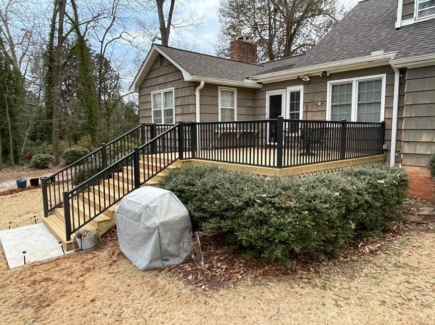 House with black railing ramp and stairs, beige siding, and a covered bush in the yard