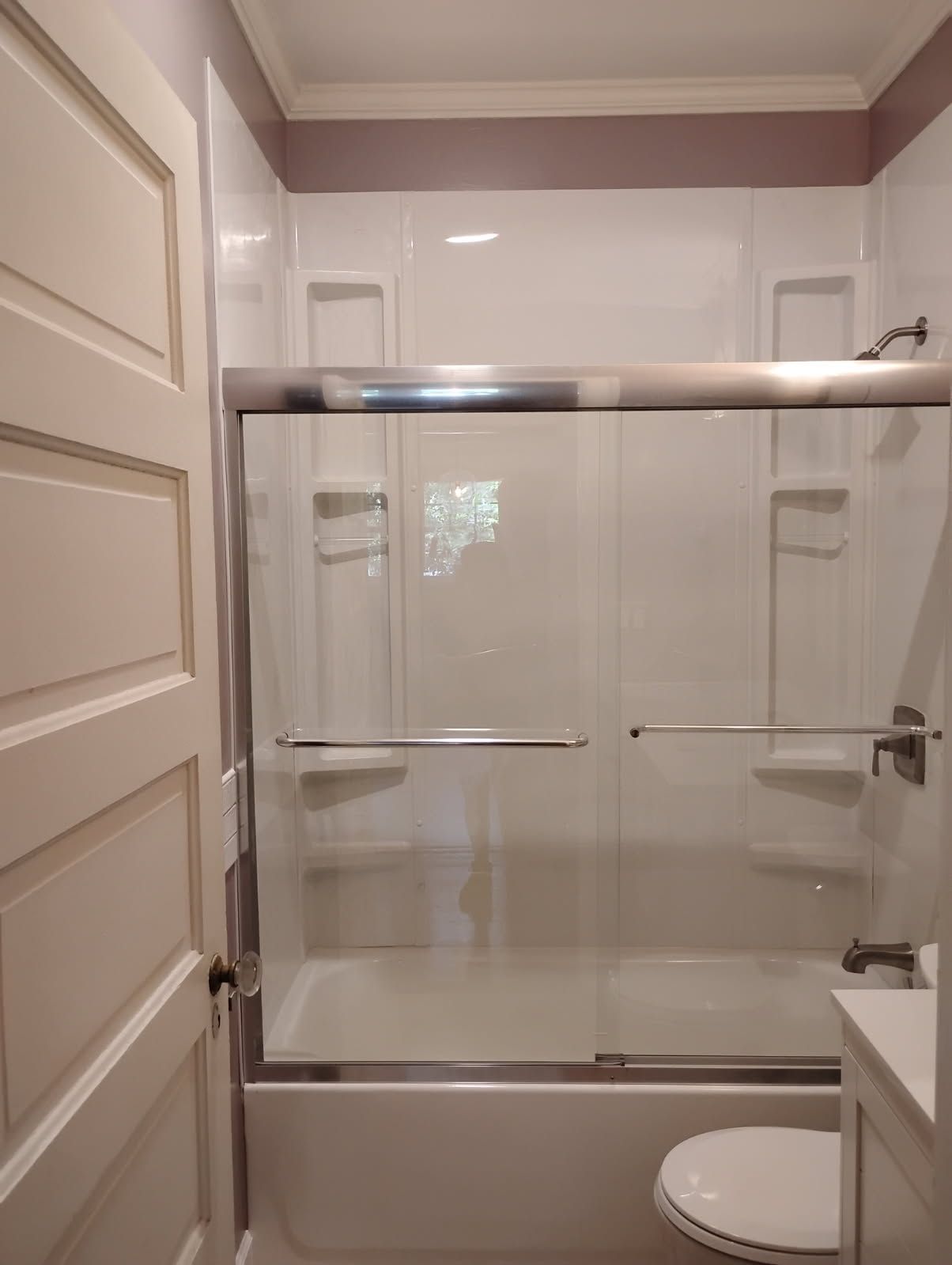 Bathroom with a glass shower enclosure, white tile walls, and a visible toilet.