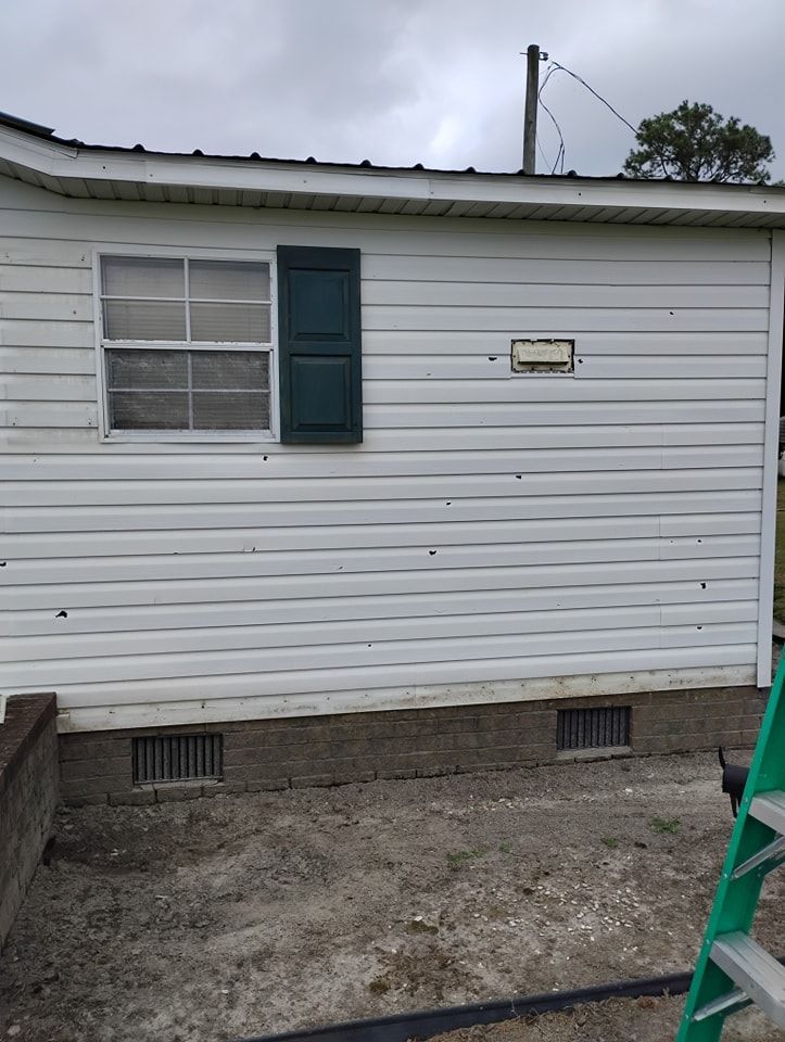 White horizontal siding on a house wall with one window, a dark shutter, a small rectangular vent, and foundation vents.