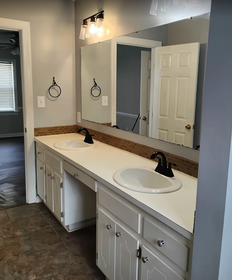 Bathroom vanity with double sinks, large mirror, and light wood cabinets