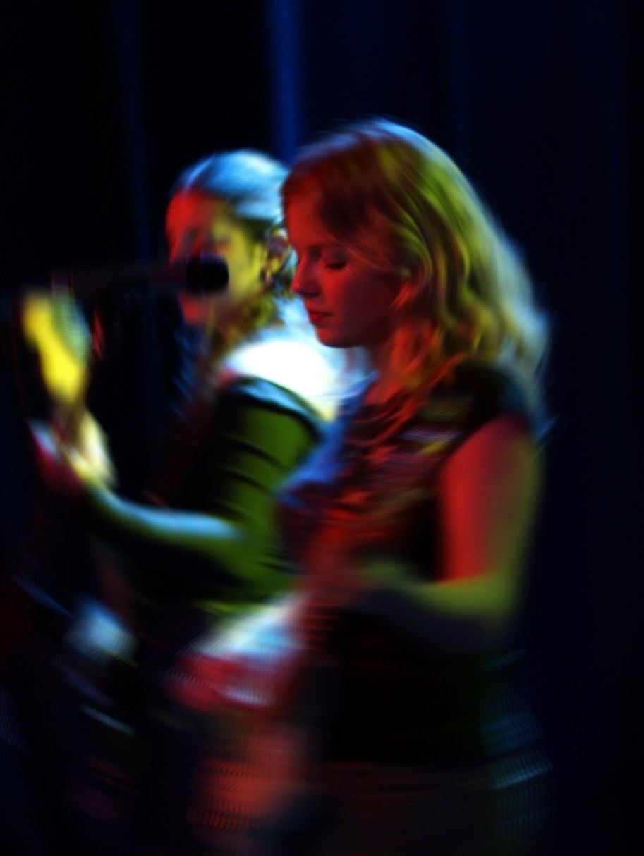 Abbey Kelkenberg performing on stage under red and blue stage lighting