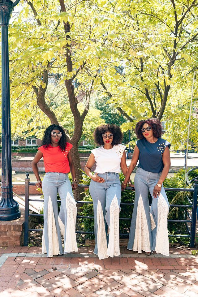 Three people pose outdoors in flared jeans with white panels, wearing tops.