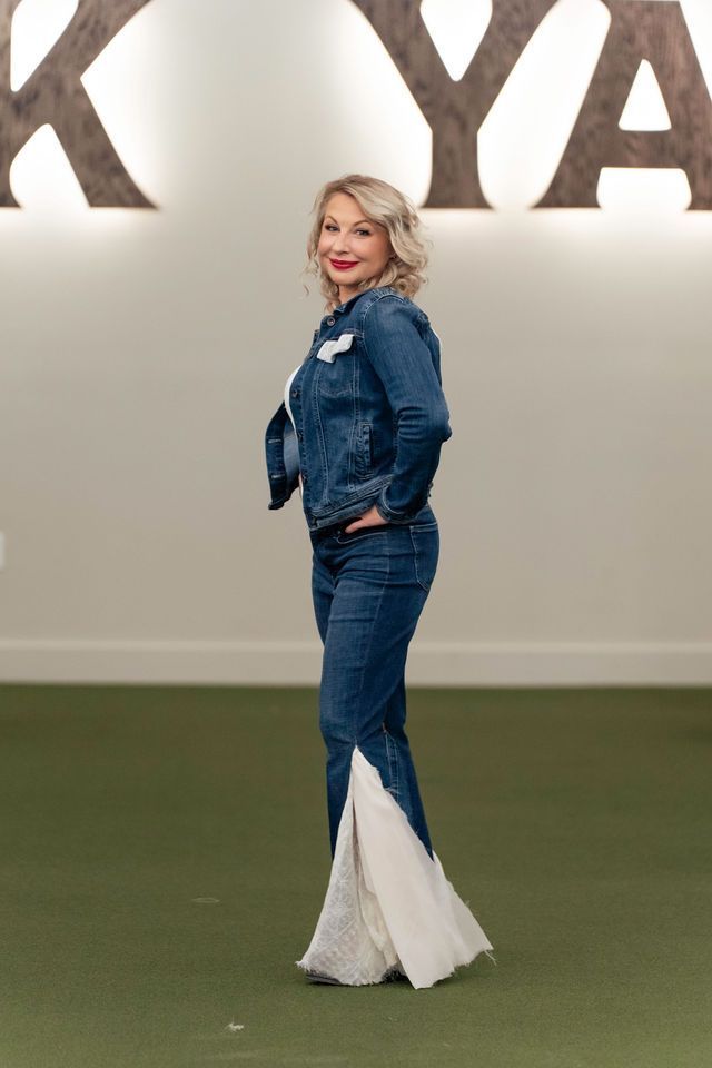 Woman in denim jacket and flared jeans with lace accents, standing on runway