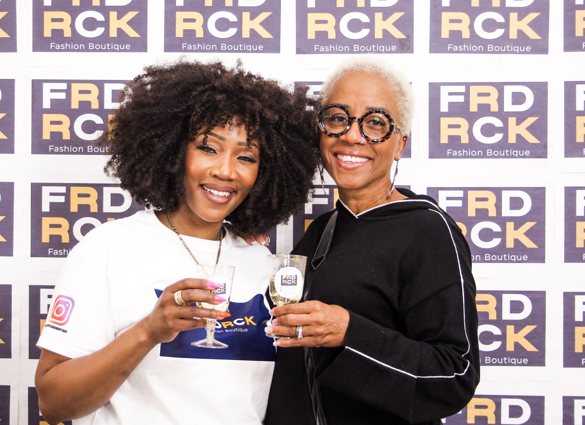 Two women smiling, holding glasses, at a