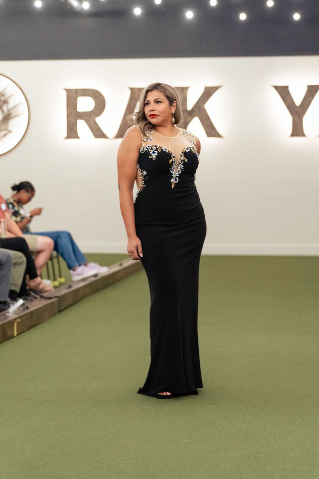 Woman in black gown, posing on green surface, with