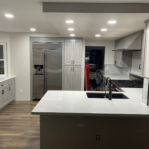 A kitchen with stainless steel appliances , white cabinets , a sink , and a refrigerator.
