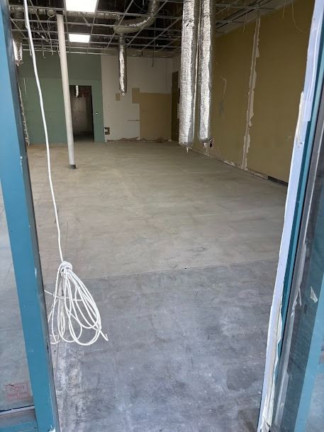 An unfinished commercial space with exposed ceiling, concrete floor, and partial walls.