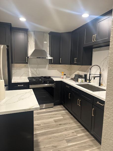 Modern black kitchen with marble countertops and stainless steel appliances.