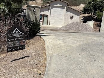 Sign for All in Remodeling with a building and gravel pile in the background.