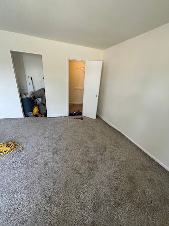 Empty room with grey carpet, white walls, and closet. Open doorway on the left.