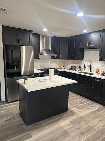 Modern kitchen with dark cabinets, stainless steel appliances, white countertops, and a kitchen island.