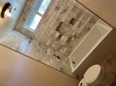 Bathroom with tiled walls, a window, bathtub, and toilet.