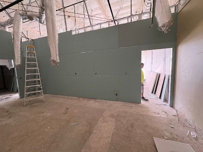 Interior under construction with drywall, ladder, and person in doorway.