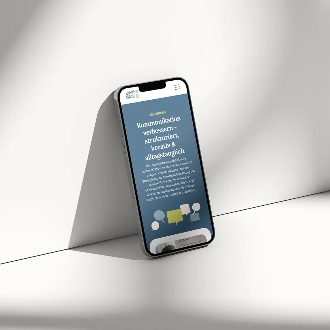 Ein Smartphone lehnt an einer Wand und zeigt einen blauen Bildschirm mit Text und Symbolen auf minimalistischem Hintergrund.