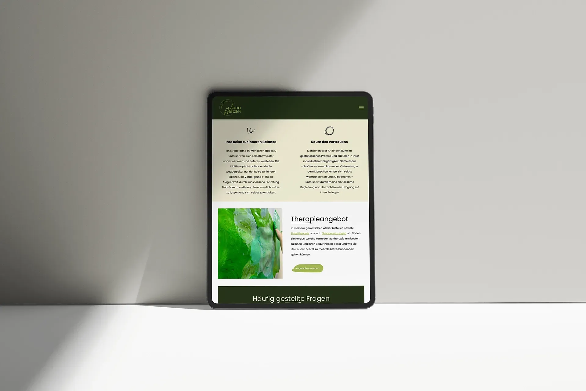 Auf einem Tisch steht ein Tablet mit der Website von Maltherapeutin Lena Metzler.