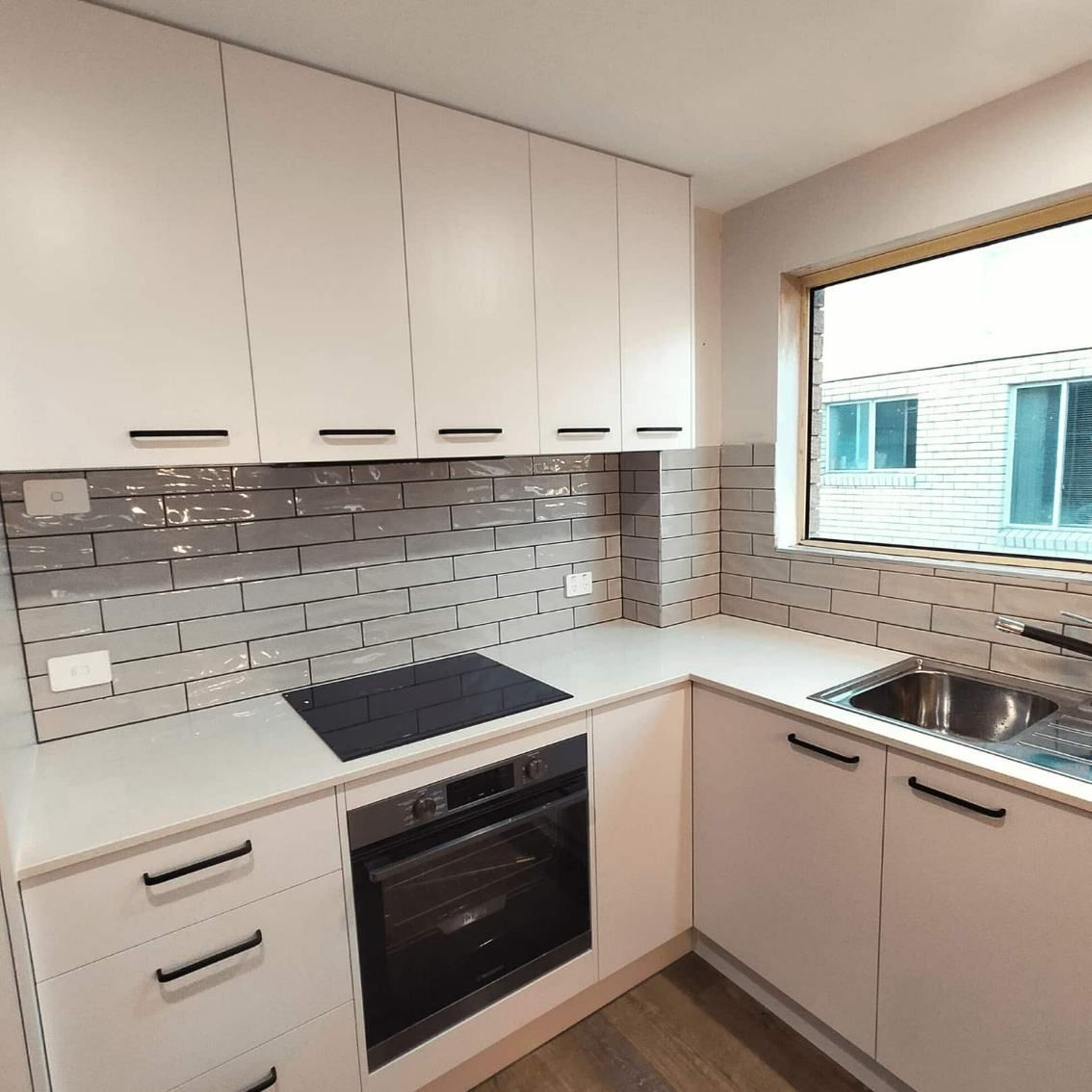 A Kitchen With White Cabinets And A Black Stove Top Oven — Nyblad Construction in Caloundra West, QLD