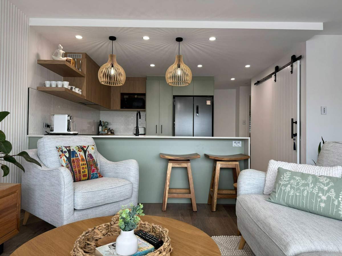 A Modern Living Room With A Comfortable Couch, A Chair, A Table, And Stools — Nyblad Construction in Caloundra West, QLD