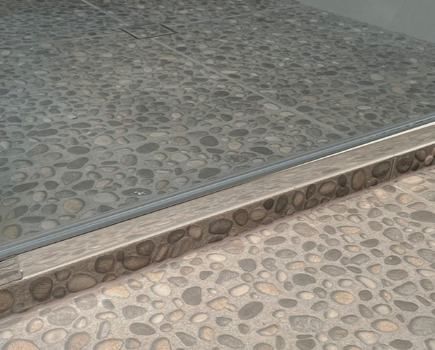 A Close Up Of A Tiled Floor With A Stainless Steel Trim — Nyblad Construction in Caloundra West, QLD